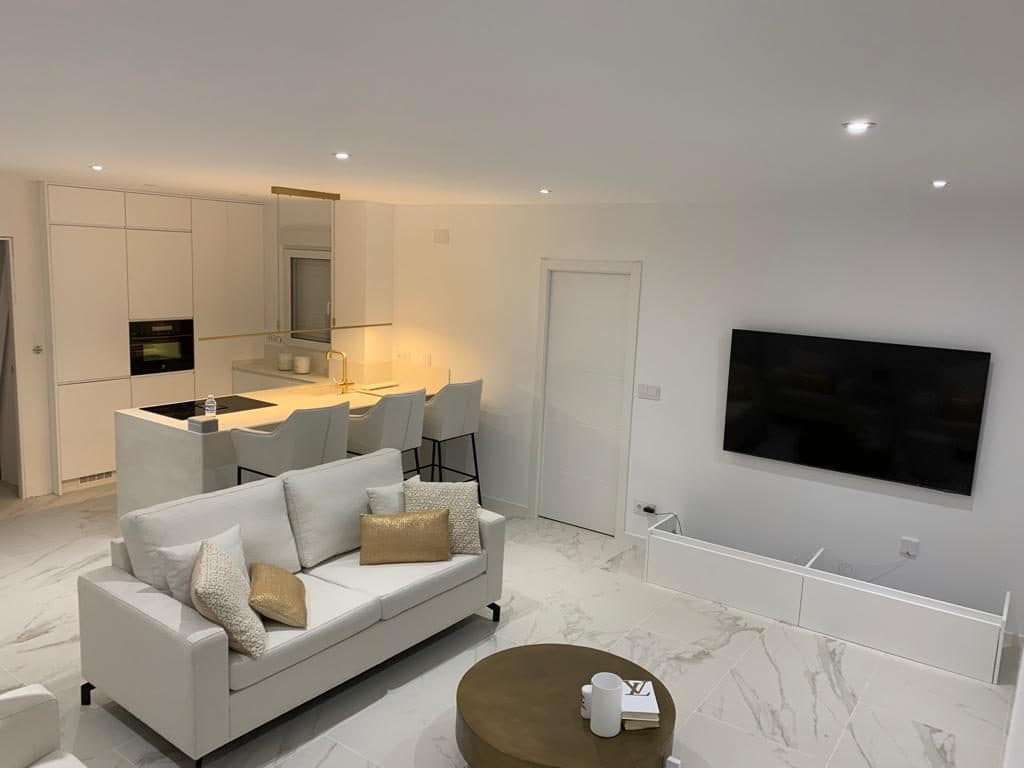 Offenes Wohnzimmer mit weißem Sofa, dahinter die Küchentheke