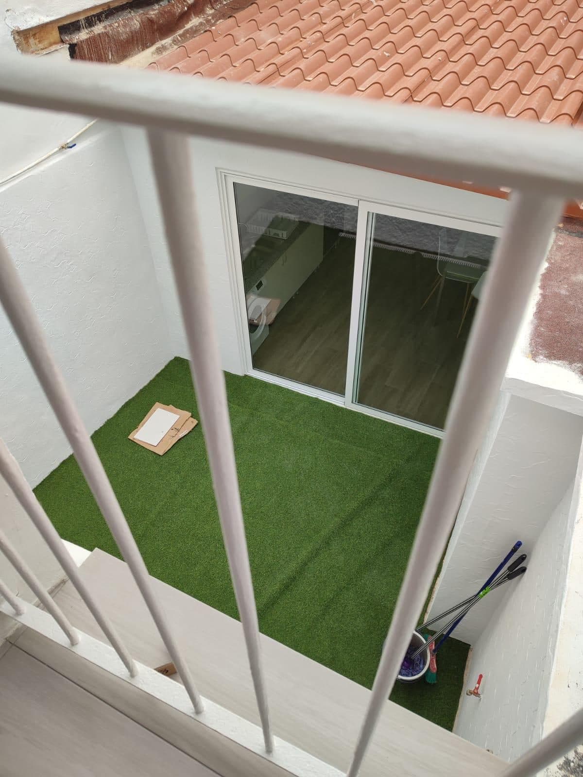 Der Innenhof vom Balkon aus, mit Kunstrasen und Aluminiumtüren
