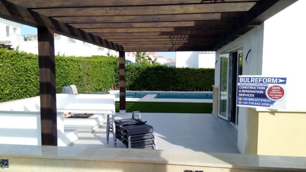 Eine Holzpergola über der Terrasse neben dem Pool
