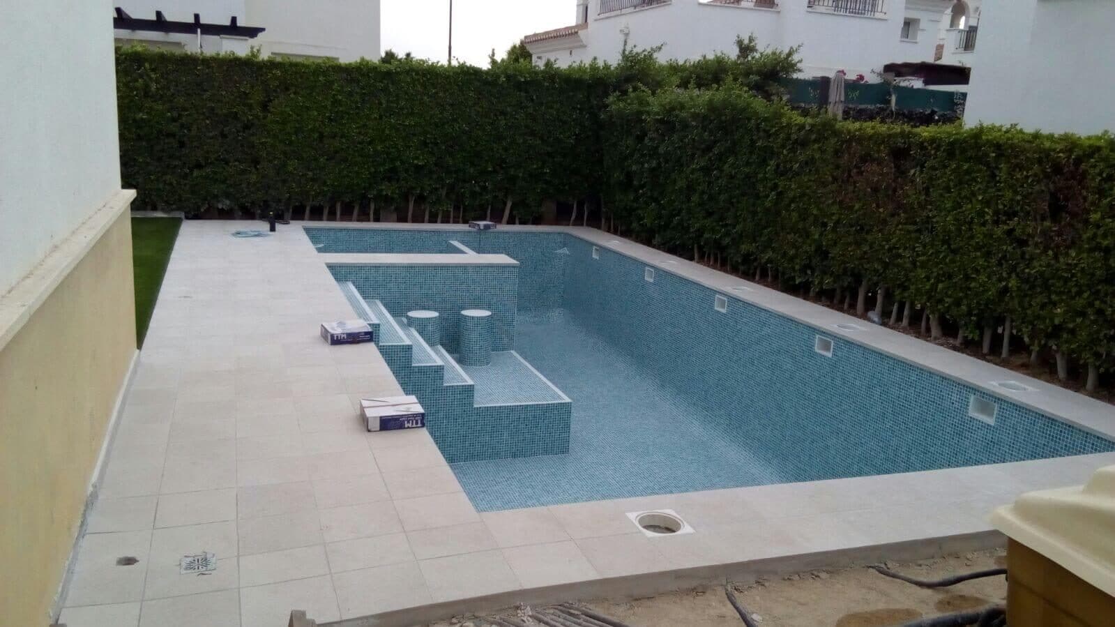 Das Poolbecken mit Treppe, vor dem Fliesen